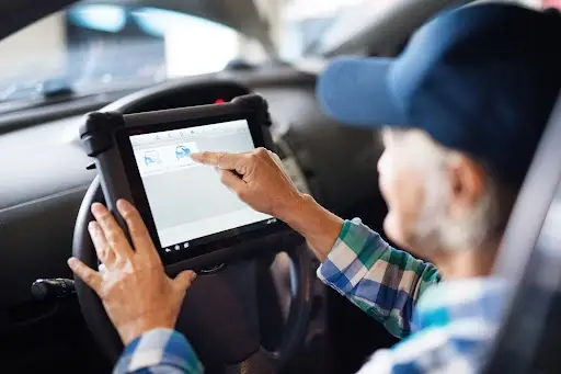senior mechanic using app in car