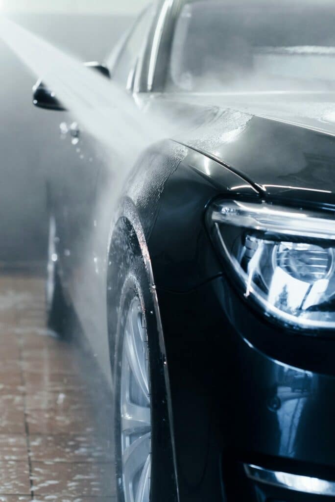 high pressured water modern black automobile get cleaned inside of car wash station e1626946365277